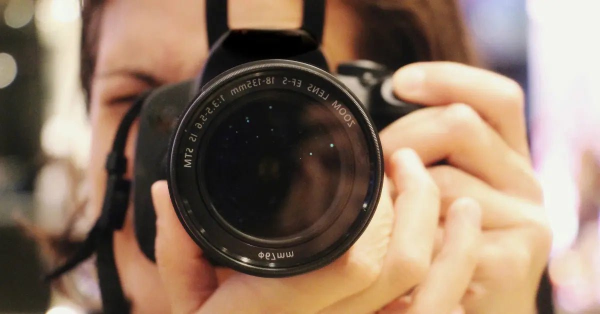 Close-up of a person holding a camera with a focus on the lens, reflecting a personal and intimate perspective in photography.